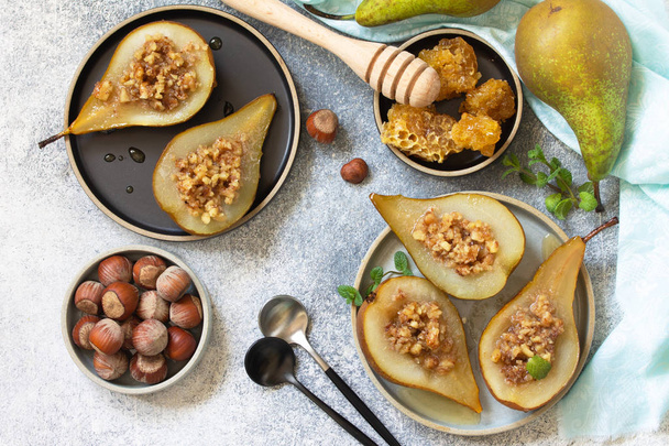 Healthy diet dessert. Baked pears with hazelnuts, honey and granola on a slate, stone or concrete background. Top view flat lay background. - Valokuva, kuva