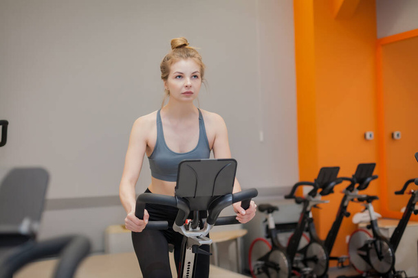 Mujer haciendo entrenamiento de entrenamiento cardiovascular en bicicleta en el gimnasio interior
 - Foto, imagen