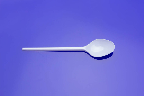Small coffee spoon and plastic fork and white. Small objects used to eat and prick food and as a measure of sugar portions to put in coffee. Objects and utensils to eat. - Foto, Imagem