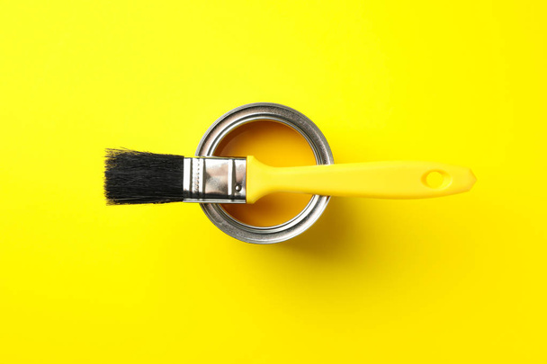 Paint can and brush on yellow background, top view - 写真・画像