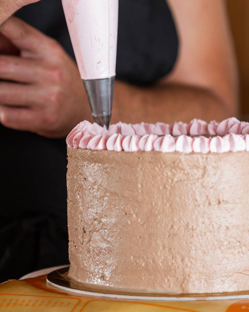 primer plano de un chef manos decoración de un pastel de cumpleaños con un alce de fresa en la parte superior de glaseado de chocolate
 - Foto, Imagen