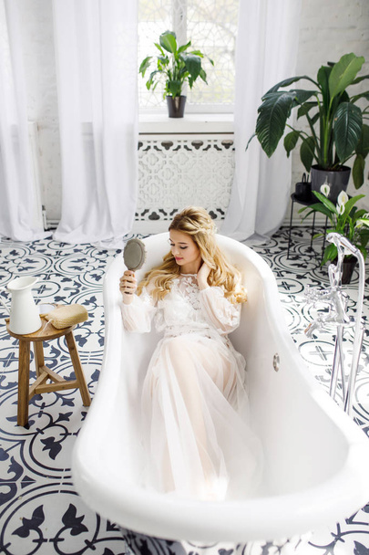 portrait of a young beautiful blonde bride in a beautiful dress in the bathroom - Fotoğraf, Görsel