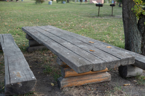 Zahradní dřevěná lavička izolovaná na zelených loukách. Dřevěný stůl a lavice na přírodu. Příroda, dovolená, léto, podzim. Piknik je čas na odpočinek s rodinou nebo přáteli. - Fotografie, Obrázek