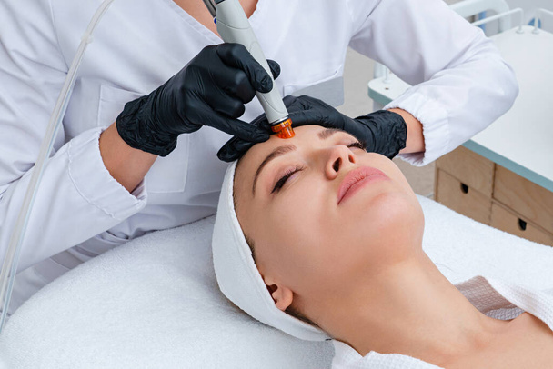 Pielęgnacja Twarzy. zbliżenie kobiety oczyszczanie twarzy w klinice kosmetologii, odkurzanie - Zdjęcie, obraz