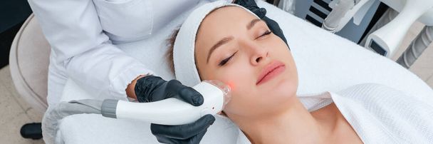 Jeune femme sous traitement laser en clinique de cosmétologie - Photo, image