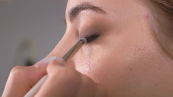 Applying makeup. Giving the eyes of the young girls expression. Stroke the eye contour with a makeup pencil. - Кадры, видео