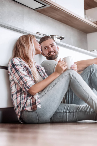 young couple drinking coffee sitting on the kitchen floor - Foto, Bild