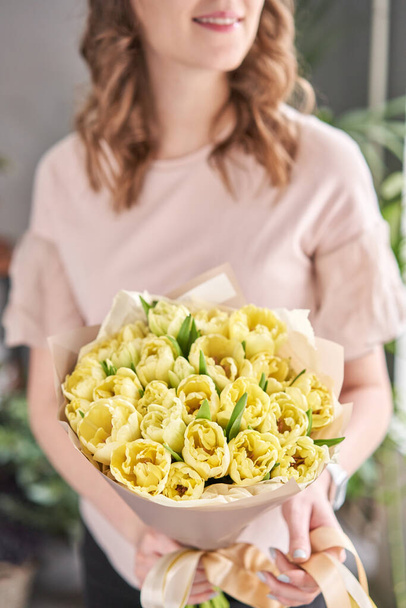 Amarelo tulipas cor pastel na mão da mulher. Jovem mulher bonita segurando um buquê de primavera. Bando de flores frescas de primavera cortadas em mãos femininas
 - Foto, Imagem