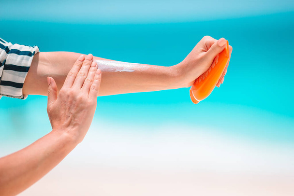 Bouteille de crème solaire en gros plan dans l'eau turquoise de fond des mains féminines
 - Photo, image