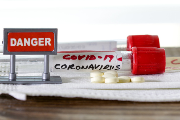 Coronavirus alias COVID-19 en tubo sanguíneo con pastillas y señal de peligro
 - Foto, imagen