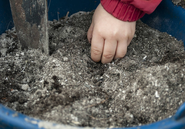 Näkyy on käsi lapsen vaivaamalla maaperän sininen muovi altaan lapio
 - Valokuva, kuva