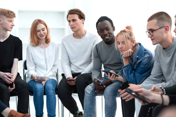 diverse young people use their smartphones sitting in line - Fotó, kép