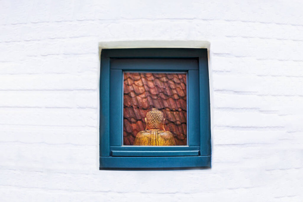 Статуя Будды в окне. Бронзовый Будда сидит сзади. Белая стена, пространство для копирования
 - Фото, изображение