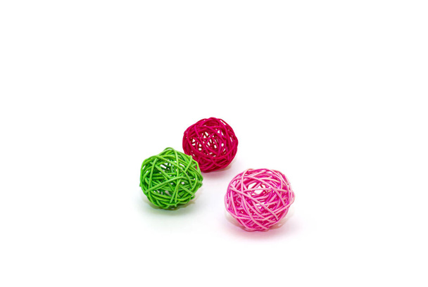 Три кульки ротанга на білому тлі. червоно-рожевий зелений
 - Фото, зображення