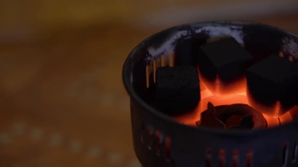 Τα κάρβουνα αναφλέγονται σε ένα παλιό ειδικό ηλεκτρικό καυστήρα κάμπινγκ. 3 μαύρα τετράγωνα κάρβουνα μαγειρεύουν και ζεσταίνονται από την καυτή θερμοκρασία σε ένα κόκκινο-καυτό σπιράλ στα δεξιά σε ένα θολό σκούρο φόντο από κοντά. - Πλάνα, βίντεο