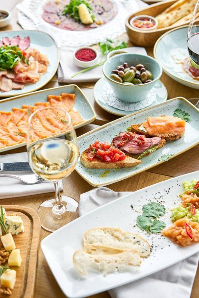 Bruschetta with beef, tomatoes and salmon.. Variety of dishes on the table. Various snacks and antipasti on the table. Restaurant menu. Italian cuisine - Zdjęcie, obraz