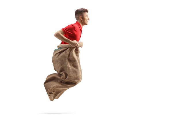 Young guy playing a game with jumping in a sack isolated on white background - Foto, Imagem