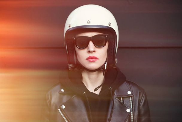 Close-up portrait of biker girl wearing sunglasses and white helmet. Dark background. - Photo, Image