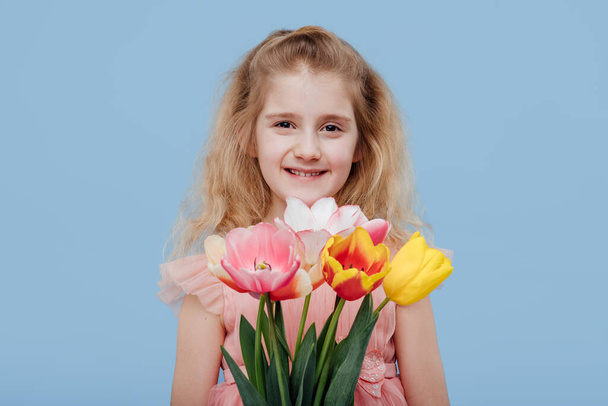 child girl in pink dress with spring flowers in hand - Фото, изображение