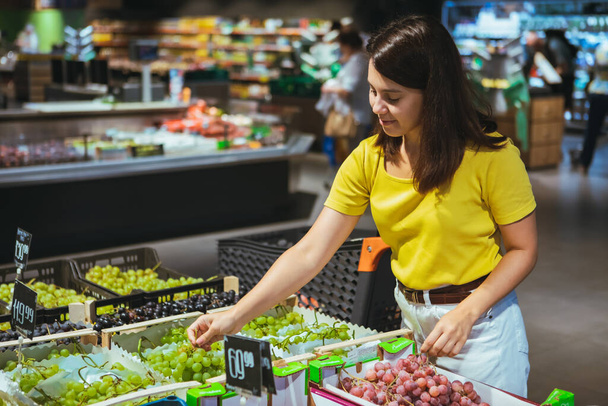woman buying grapes in store grocery shopping concept - Photo, Image