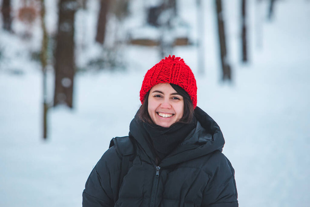mooie lachende vrouw in rode hoed winter outfit gesneeuwd weer - Foto, afbeelding