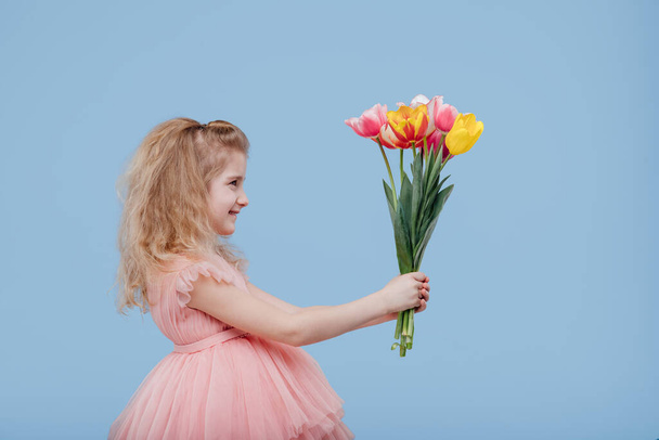 little girl in pink dress with spring flowers in hand - Fotó, kép
