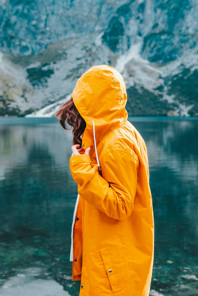 Tatra Ulusal Parkı 'ndaki Lake Beach' te sarı yağmurluklu bir kadın. - Fotoğraf, Görsel