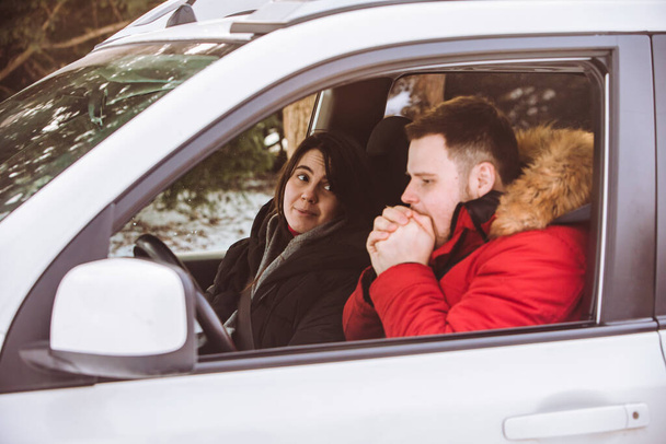 Man en vrouw in de auto in winterkleding. roadtrip - Foto, afbeelding
