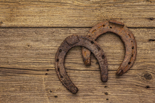 Cast iron metal horse horseshoes. Good luck symbol, St.Patrick's Day concept. Old wooden background, horse accessories, top view - Zdjęcie, obraz