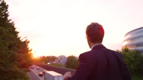 Linsenschlag aus nächster Nähe: Fröhlicher junger Manager streckt bei Sonnenaufgang die Arme aus. - Filmmaterial, Video