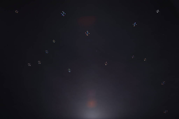 Veel zeepbel bal in de lucht blazen in de wind, over donkere zwarte achtergrond met licht uit de bodem - Foto, afbeelding