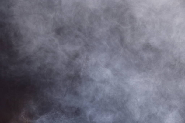 Denso Fluffy Puffs de fumo branco e nevoeiro em fundo preto, nuvens de fumaça abstratas, todo o movimento desfocado, intenção fora de foco e alto baixo contraste de exposição, espaço de cópia para logotipo do texto - Foto, Imagem