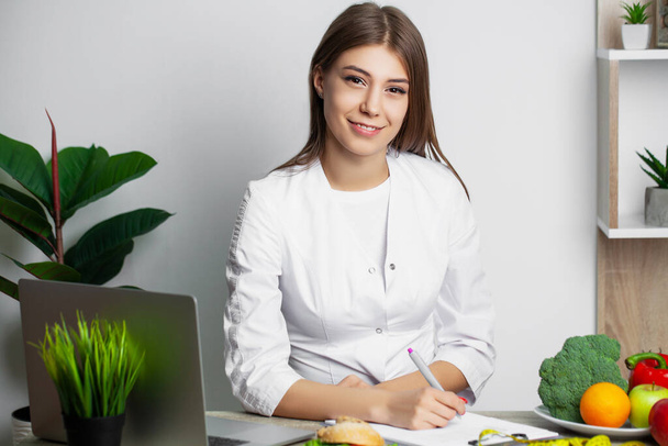 Female nutritionist with fruits working at her desk - Photo, Image