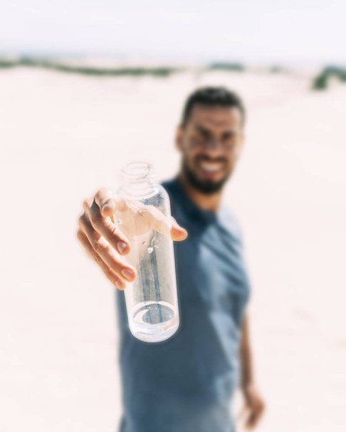 Африканский молодой мужчина (берберский фон) предлагает последний глоток воды в пустыне. Изменение климата вызвало длительные и суровые засухи. Береберское гостеприимство - одно из их величайших достоинств
. - Фото, изображение