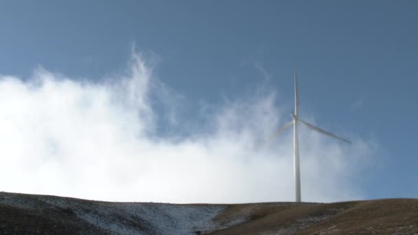 Wind gust with cloud rises above hillside which blows and spins wind turbine blades. - Footage, Video