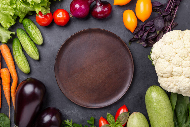 Wood plate and fresh farmers garden vegetables on stone background. Harvest time. Top view - Image - Fotoğraf, Görsel