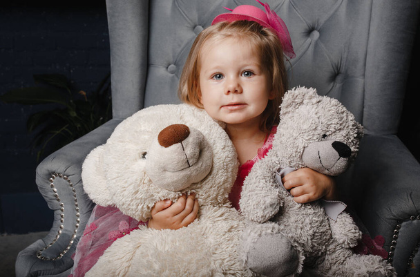 Μικρό κορίτσι με ροζ φόρεμα που κρατάει 2 αρκουδάκια στα χέρια της - Φωτογραφία, εικόνα