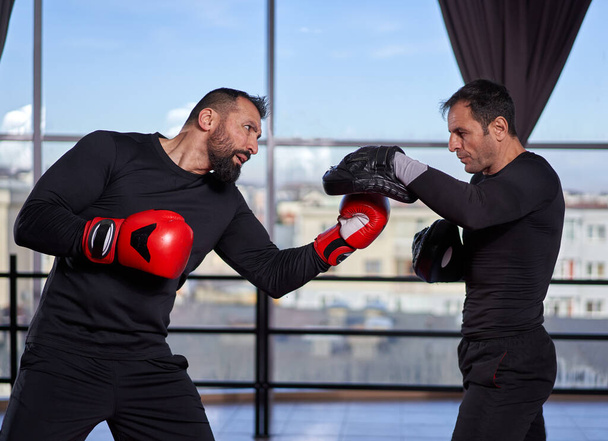 Boxeador golpeando guantes con su entrenador en el gimnasio
 - Foto, Imagen