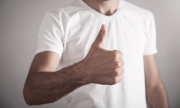 Man in white shirt making a thumbs up gesture. - Valokuva, kuva