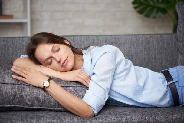 Donna stanca sta dormendo in vestiti su un divano a casa
 - Foto, immagini
