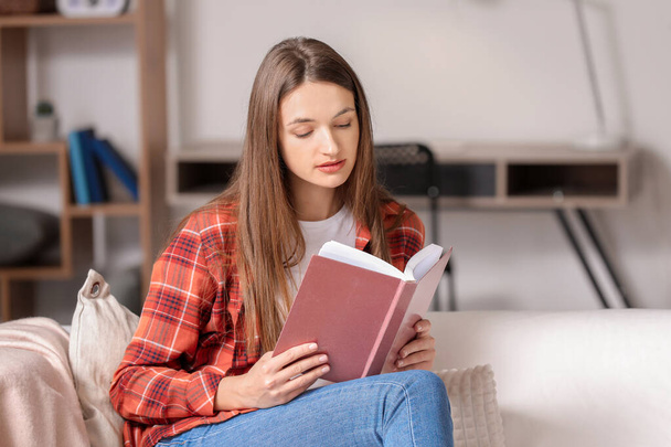 Beautiful young woman reading book at home - Photo, Image