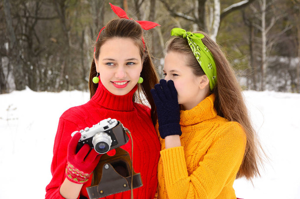 Portrait of pin-up girls in bright sweaters and scarves, photographing in the winter forest. Close-up - Foto, afbeelding