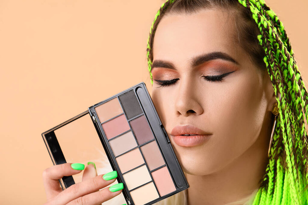 Transgender makeup artist with decorative cosmetics on color background - Photo, Image