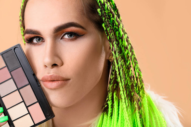 Transgender makeup artist with decorative cosmetics on color background - Foto, afbeelding