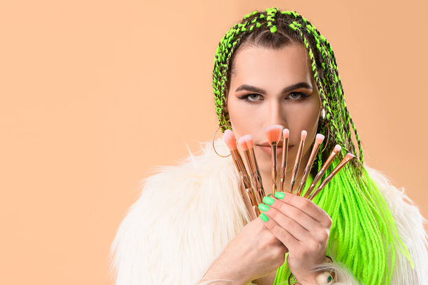 Transgender makeup artist with brushes on color background - Foto, immagini