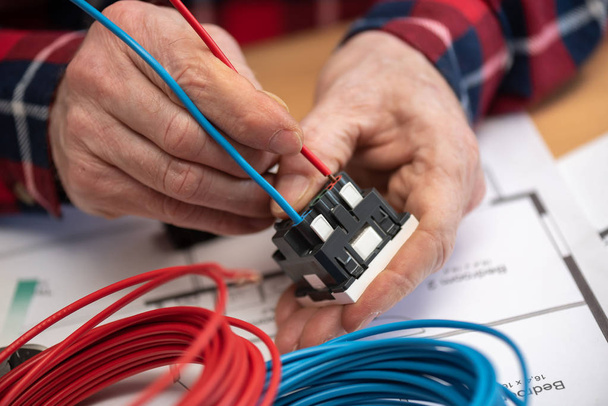 Mani di elettricista che collegano un filo in una presa di corrente
 - Foto, immagini