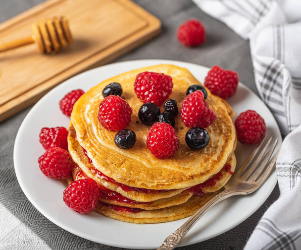 Sweet homemade pancakes with raspberries and blueberries on white plate. - Zdjęcie, obraz