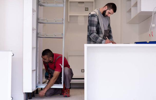 İki profesyonel işçi yeni moda modern mutfak mobilyalarını kuruyor. - Fotoğraf, Görsel