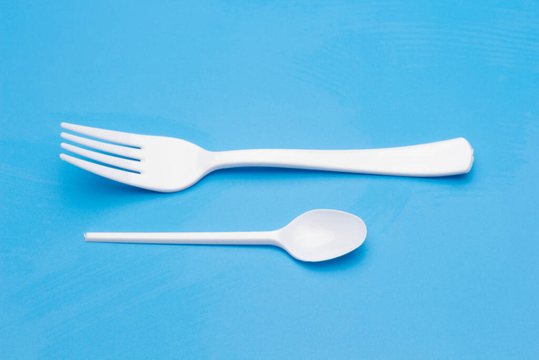 Cutlery for eating white and made of plastic and transparent glass cups; Cutlery and glasses teaspoons for coffee and for rationing small amounts of sugar, fork for pricking food, glasses for drinking - 写真・画像