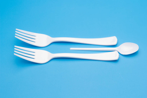 Cutlery for eating white and made of plastic and transparent glass cups; Cutlery and glasses teaspoons for coffee and for rationing small amounts of sugar, fork for pricking food, glasses for drinking - Fotoğraf, Görsel